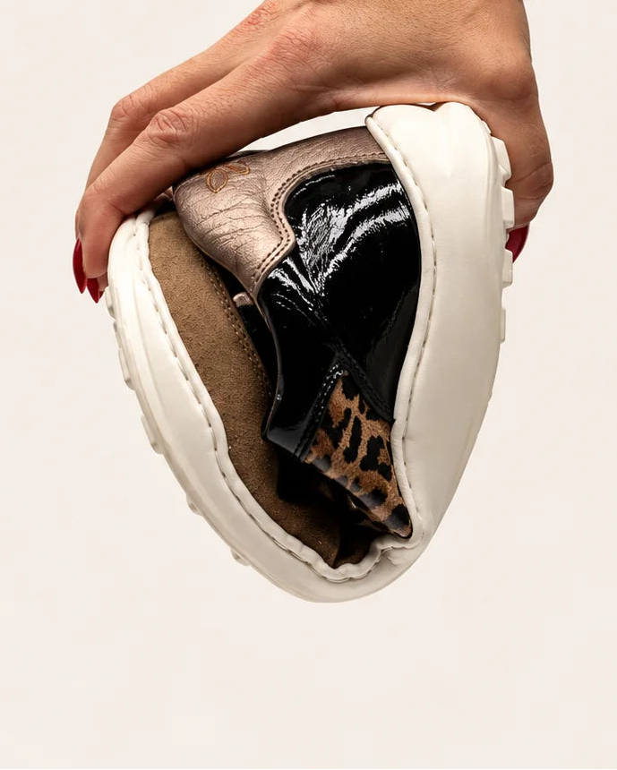 Mano doblando la deportiva barefoot de transición de mujer modelo LÍA Chic en piel negro, leopardo y camel de Valenta Unic para mostrar la flexibilidad de su suela